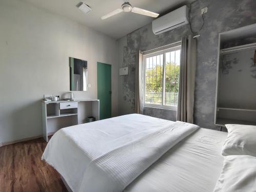 a bedroom with a large white bed and a window at Ocean Pearl in Gulhi