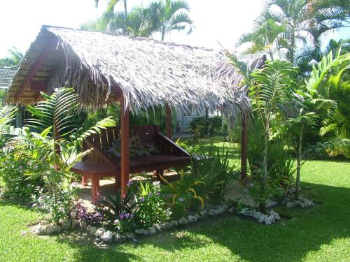 a hut with a straw roof in a garden at Pacific Lagoon Apartments in Port Vila