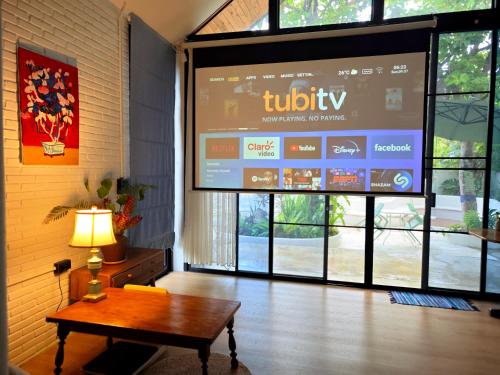 a large television screen in a room with a table at Fieldlight Pool Villa -Rice View &private pool云上稻影 in Mae Rim