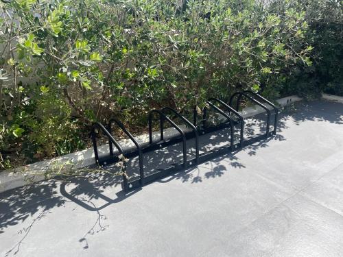 a black metal bench on a sidewalk next to bushes at Casa Quetta in Bari