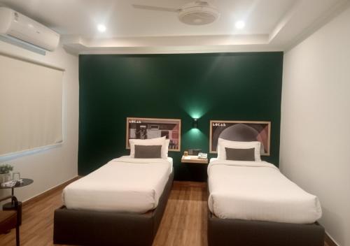 two beds in a room with a green wall at Hotel Oban in Lahore