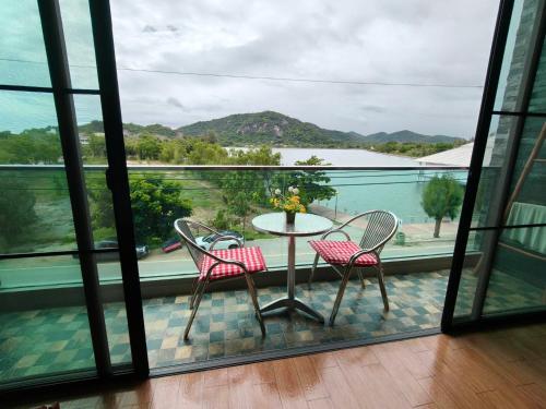 a balcony with a table and chairs and a view of the water at Turtle Nest in Khao Tao