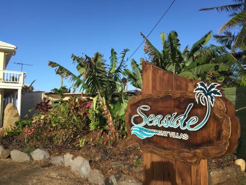a sign for a seaside resort with palm trees at Seaside Beachfront Villas Rarotonga in Rarotonga