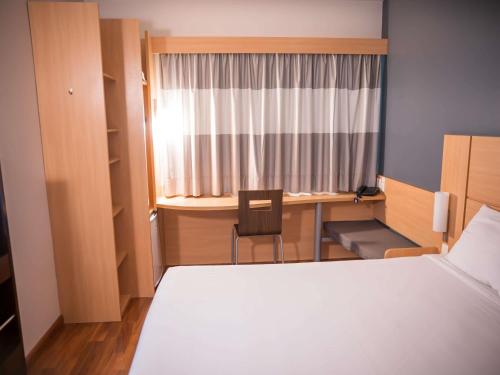 a bedroom with a bed and a desk and a window at ibis Itu Plaza Shopping in Itu
