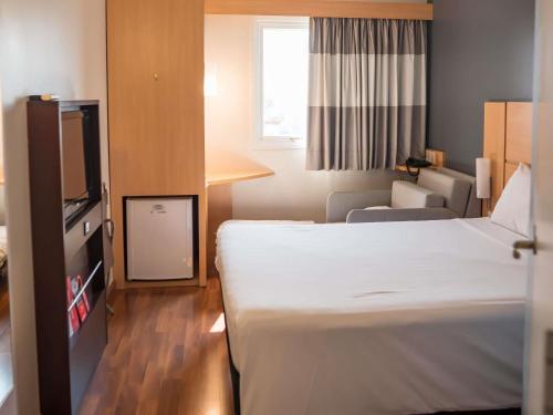 a small hotel room with a bed and a chair at ibis Itu Plaza Shopping in Itu