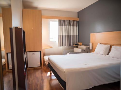 a hotel room with a large bed and a chair at ibis Itu Plaza Shopping in Itu