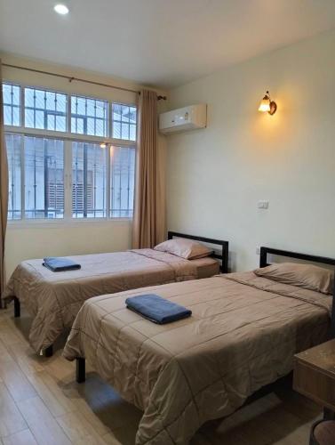 two beds in a room with a window at Mangkon Hostel in Bangkok