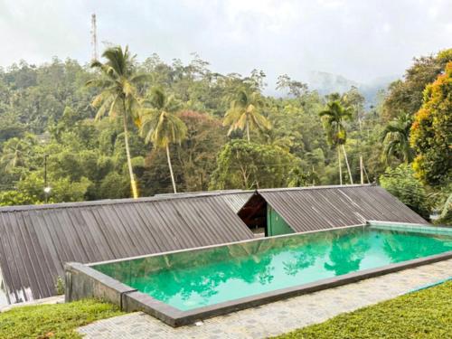 a swimming pool in front of a house with a mountain at Sinharaja Forest Sanctuary in Deniyaya