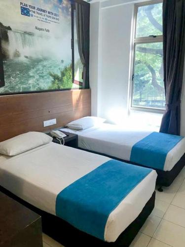 two beds in a hotel room with a window at Hotel Zamburger Bangsar (Previously Koptown Hotel Bangsar) in Kuala Lumpur