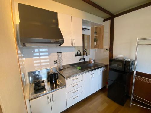 a kitchen with white cabinets and a sink and a microwave at guesthouse Yokomachi in Shingu