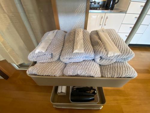 four towels are stacked on a shelf in a kitchen at guesthouse Yokomachi in Shingu