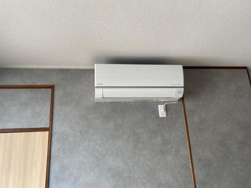 a white air conditioner on the wall of a room at guesthouse Yokomachi in Shingu