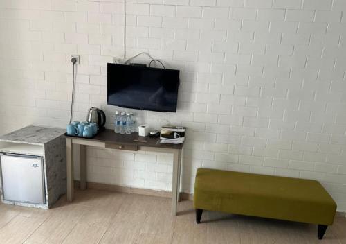 a room with a desk with a tv on a wall at D'Lima Beach Inn in Pantai Cenang
