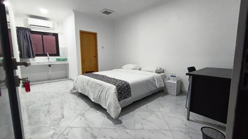a white bedroom with a bed and a television at Hotel Wisma Syariah in Jakarta