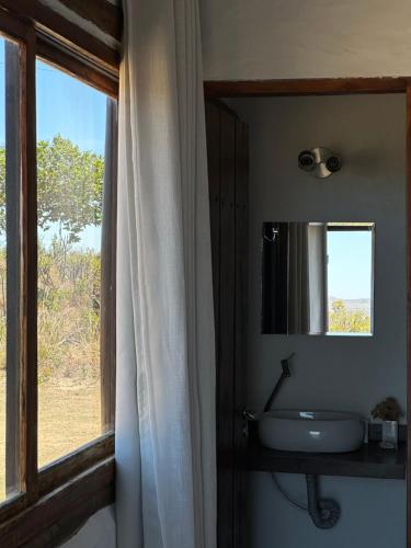 a bathroom with a sink and a mirror and a window at Cachoeira e Pousada Paraíso dos Pândavas in Alto Paraíso de Goiás