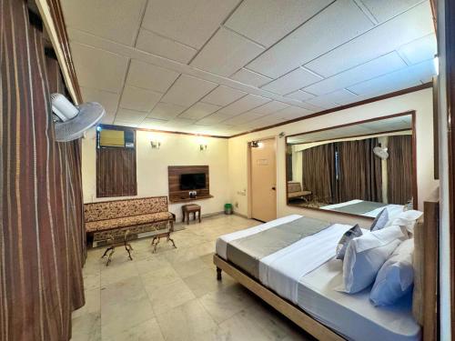a bedroom with a large bed and a living room at asar CP Outer Circle by Orion Hotels in New Delhi