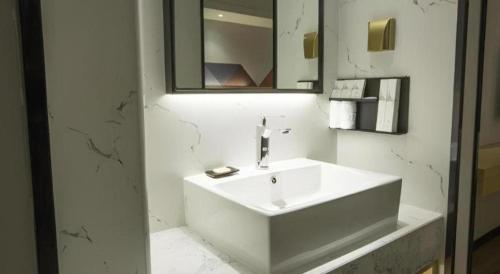 a white bathroom with a sink and a mirror at Borrman Hotel Zhuhai Gongbei Port Fuhuali Light Rail in Zhuhai