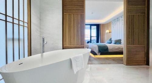 a bathroom with a tub and a bedroom with a bed at Kunming Dianchi Garden Hotel & Spa in Kunming