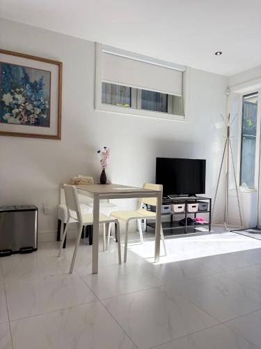 a living room with a table and chairs and a tv at Fancy Family Suite with Parking near UBC in Vancouver