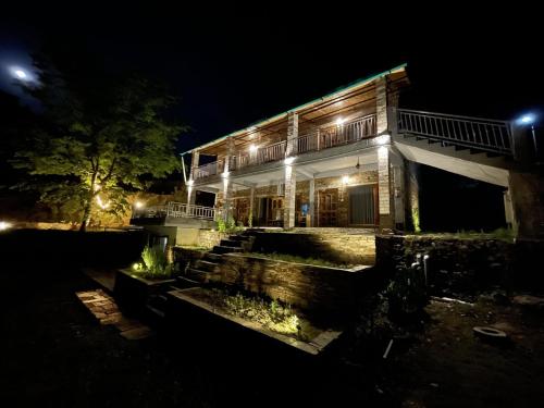 a house lit up at night with lights at Himkosi Farm by the River in Almora