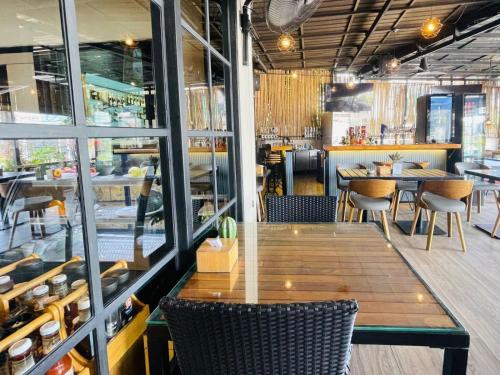 een restaurant met een houten tafel, stoelen en ramen bij Breakers Hotel Rawai in Rawai Beach
