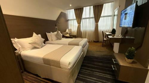 a hotel room with two beds and a television at Lamar Ajyad First Hotel Tower A in Makkah