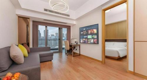 a hotel room with a bed and a couch and a desk at Huafa Executive Apartment Hotel Zhuhai in Zhuhai