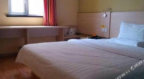 a hotel room with a large bed and a desk at 7 Days Inn Baoding Railway Station in Baoding