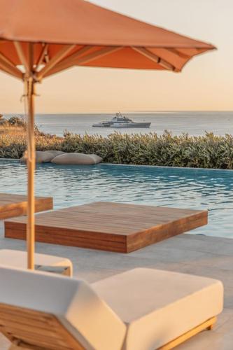 a swimming pool with an umbrella and a cruise ship at Aelo Mykonos Hotel in Paradise Beach