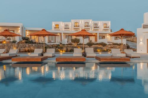 a pool with chairs and umbrellas in front of a hotel at Aelo Mykonos Hotel in Paradise Beach