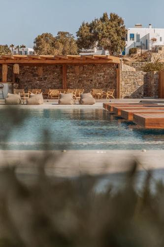 a swimming pool with chairs and a stone wall at Aelo Mykonos Hotel in Paradise Beach