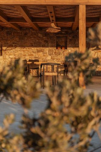 a patio with tables and chairs and a stone wall at Aelo Mykonos Hotel in Paradise Beach
