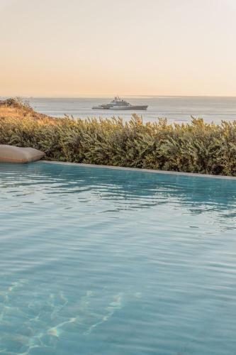 a large swimming pool with a cruise ship in the ocean at Aelo Mykonos Hotel in Paradise Beach