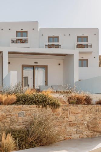 a white house with windows and a stone wall at Aelo Mykonos Hotel in Paradise Beach