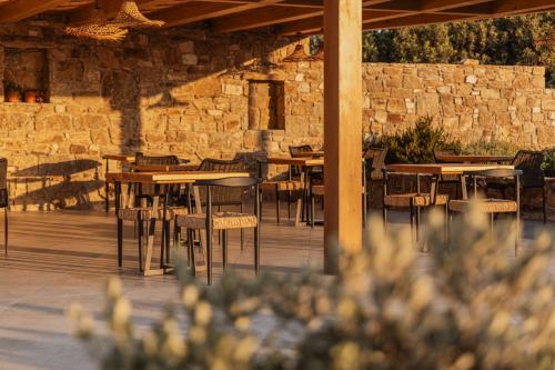 a patio with tables and chairs and a stone wall at Aelo Mykonos Hotel in Paradise Beach