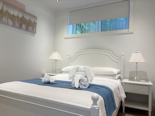a white bedroom with a bed with towels on it at Fancy Family Suite with Parking near UBC in Vancouver