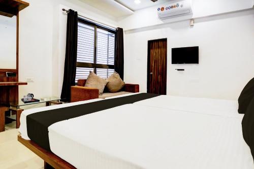 a bedroom with a white bed and a tv at Hotel O Nashik Road Formerly The Address Hotel in Nashik