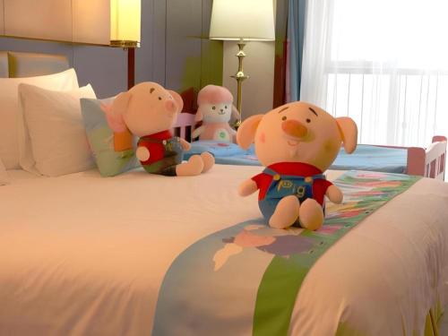 three stuffed animals sitting on top of a bed at New Century Grand Hotel Xi'an Xizang Building in Xi'an