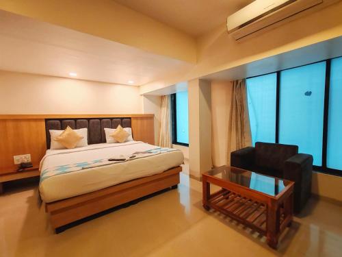 a bedroom with a bed and a chair and a table at Hotel Aishwarya Residency in Nerul