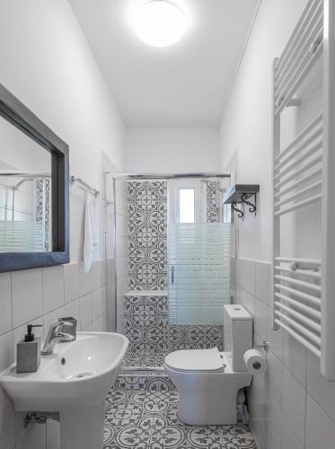a white bathroom with a sink and a toilet at Han’s Maisonette in Porto Heli