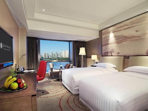 a hotel room with two beds and a television at Pullman Xiamen Powerlong in Xiamen