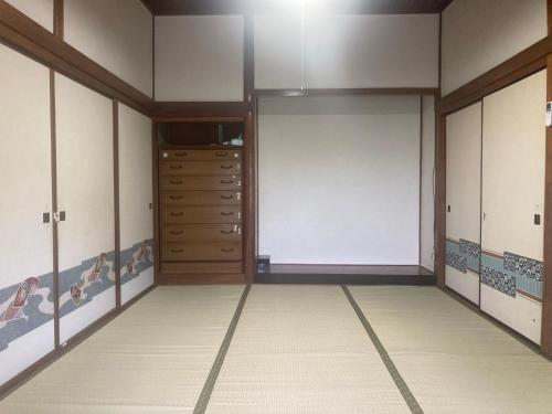 a walk in closet with wooden doors and tile floors at しまなみゲストハウス南風荘 in Imabari