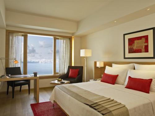 a hotel room with a bed and a desk and a window at Trident Nariman Point in Mumbai
