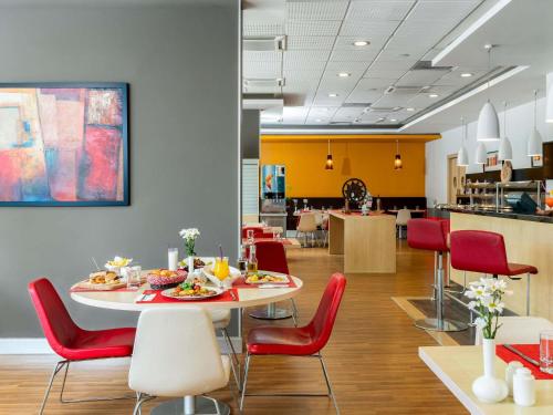 a dining room with a table and red chairs at Ibis Izmir Alsancak in Izmir