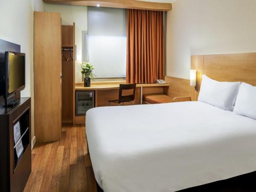 a hotel room with a large bed and a desk at Ibis Izmir Alsancak in Izmir