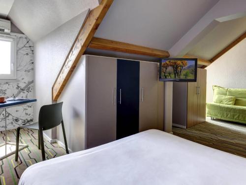 a bedroom with a bed and a window with a tv at ibis Styles Périgueux Trélissac in Trélissac