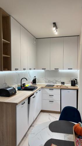 a white kitchen with white cabinets and a table at Rajska7712 in Wrocław