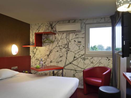 a hotel room with a bed and a red chair at ibis Styles Périgueux Trélissac in Trélissac