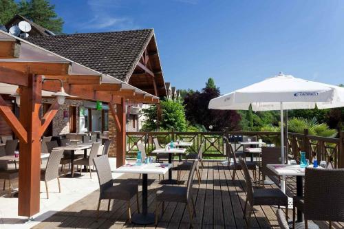 a patio with tables and chairs and an umbrella at ibis Styles Périgueux Trélissac in Trélissac