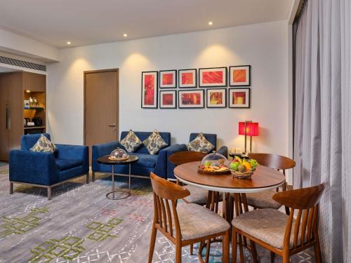 a living room with a couch and a table and chairs at Novotel Ahmedabad in Ahmedabad